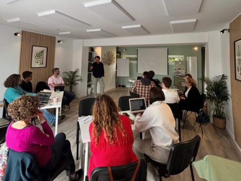 Atelier collaboratif dans la salle Hestia : participants répartis en petits îlots de travail pour favoriser les échanges et la réflexion en équipe lors d'un séminaire à l'Espace Tulsi.