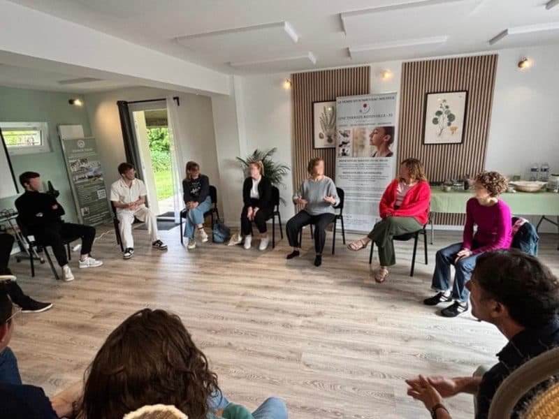 Participants réunis en cercle de discussion dans la salle Hestia pour un atelier de cohésion d'équipe, favorisant l'écoute et le dialogue au sein de l'Espace Tulsi.