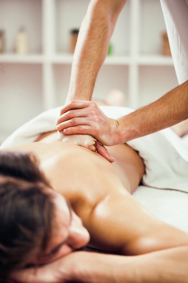 Massage relaxant en cours, avec un praticien appliquant des techniques de soin sur le dos d'un client.