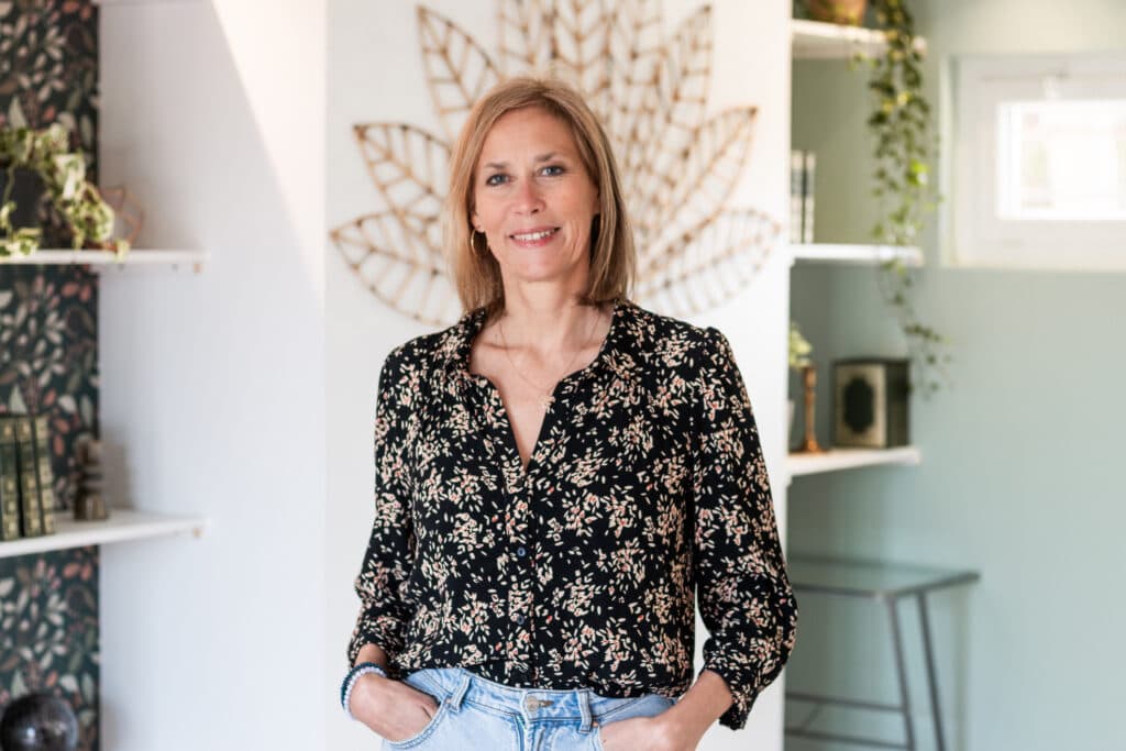 Portrait de FABIENNE VERRON dans un espace chaleureux, décoré de plantes et d'éléments naturels.