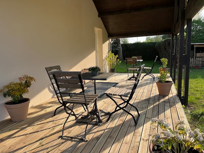 Espace extérieur verdoyant de l'Espace Tulsi, avec des tables et chaises, parfait pour un thé au calme